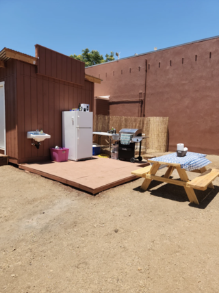 Outdoor kitchen complete with sink, refrigerator, grill, and picnic table.